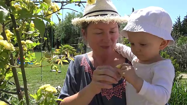 可爱的小女孩和妈妈在美丽的花园里散步视频素材