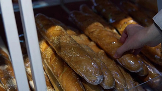 顾客在超市里选择法棍面包。视频素材