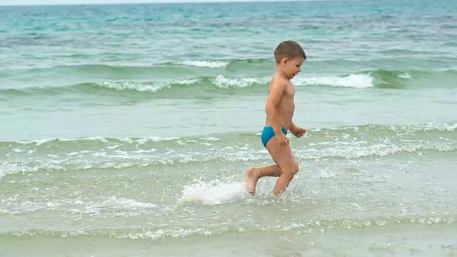 快乐的小男孩在热带海滩的海边跑步视频素材