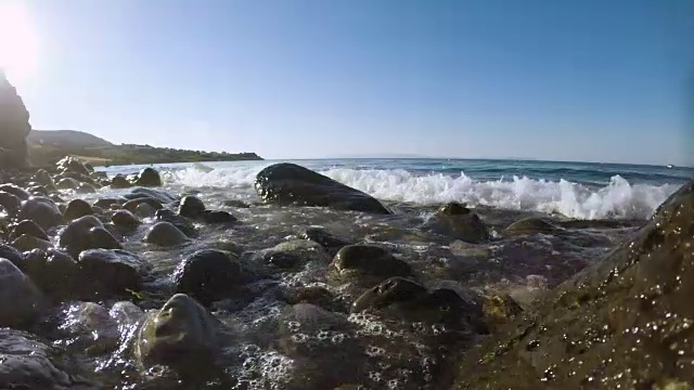 海浪和水溅到多石的海滩上的石头上。视频素材