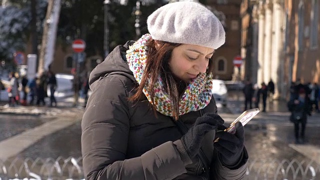 冷天里在街上用智能手机打字的漂亮年轻女人视频素材