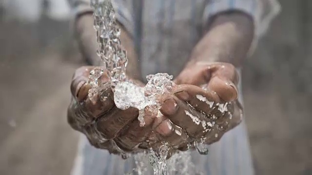 纯净水和淡水落在穷人的手上的慢动作镜头视频素材