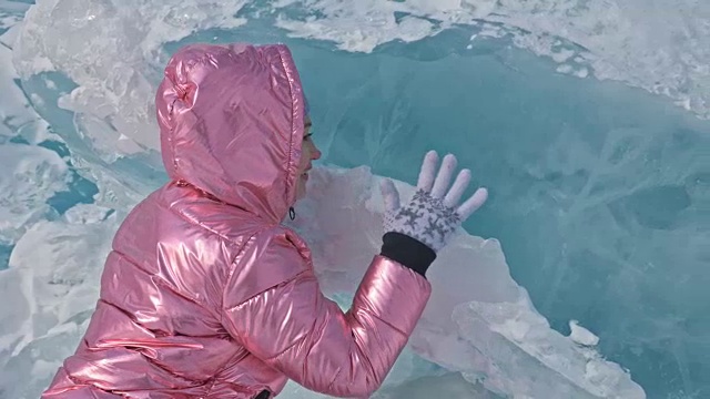 一个女孩走在贝加尔湖破裂的冰面上。一名女旅行者探索并看着一块浮冰。这是自然界中最神奇最纯净的地方。冰环绕着旅行者所有的旅程。视频素材