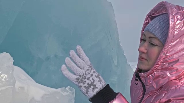 一个女孩走在贝加尔湖破裂的冰面上。一名女旅行者探索并看着一块浮冰。这是自然界中最神奇最纯净的地方。冰环绕着旅行者所有的旅程。视频素材