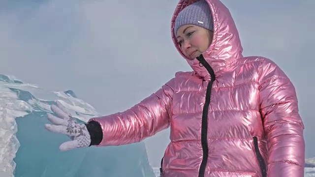 一个女孩走在贝加尔湖破裂的冰面上。一名女旅行者探索并看着一块浮冰。这是自然界中最神奇最纯净的地方。冰环绕着旅行者所有的旅程。视频素材