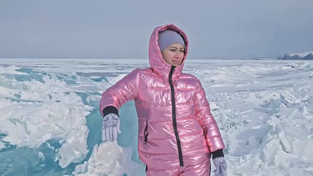 一个女孩走在贝加尔湖破裂的冰面上。一名女旅行者探索并看着一块浮冰。这是自然界中最神奇最纯净的地方。冰环绕着旅行者所有的旅程。视频素材