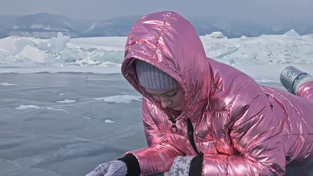 一个女孩走在贝加尔湖破裂的冰面上。一名女旅行者探索并看着一块浮冰。这是自然界中最神奇最纯净的地方。冰环绕着旅行者所有的旅程。视频素材