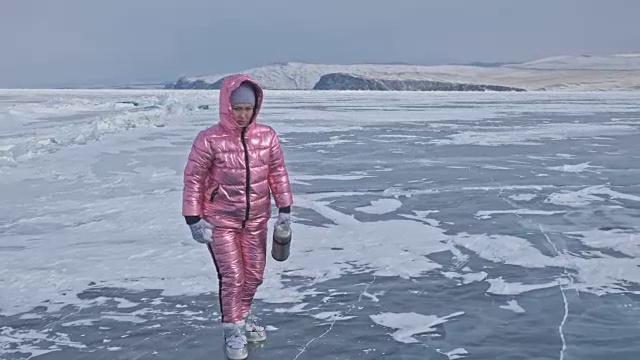 一个女孩走在贝加尔湖破裂的冰面上。一名女旅行者探索并看着一块浮冰。这是自然界中最神奇最纯净的地方。冰环绕着旅行者所有的旅程。视频素材