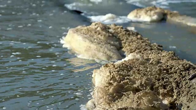 河水表面的棕色泡沫，是水污染造成的。废物汇入河中。视频素材