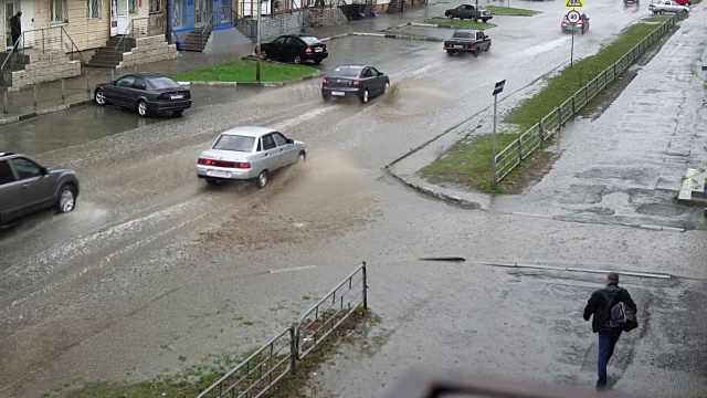 汽车在雨中行驶在被洪水淹没的道路上，慢镜头。视频素材