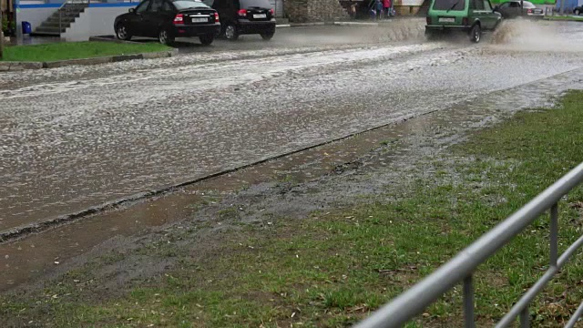 汽车在雨中行驶在被洪水淹没的道路上，慢镜头。视频素材