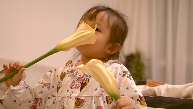 泰国小女孩正穿着睡衣在卧室里闻着花香视频素材