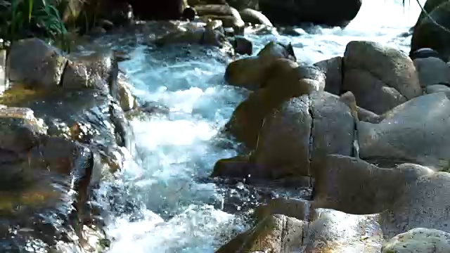 在山区湍急的河流中，小溪的水流近距离。水流在岩石密布的河里迅速流动。山河中水流湍急视频素材