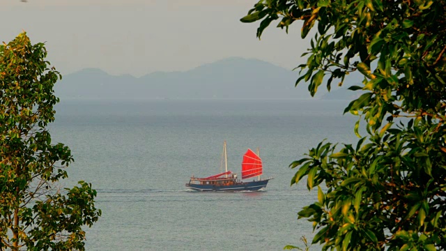 日落时分，一艘中国传统的红帆船在海上漂浮视频素材