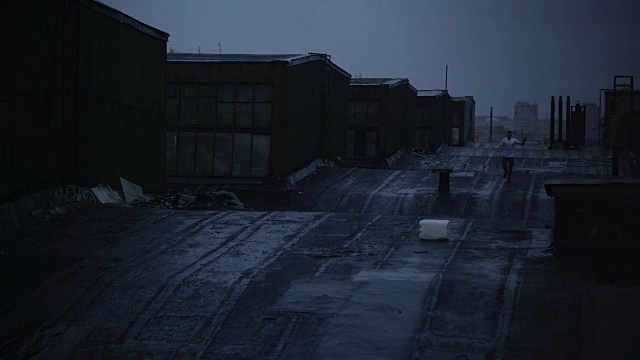 年轻人在雨中湿透的屋顶上奔跑视频素材