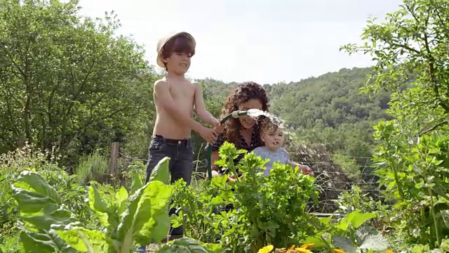 妈妈和宝宝看着男孩给植物浇水视频素材