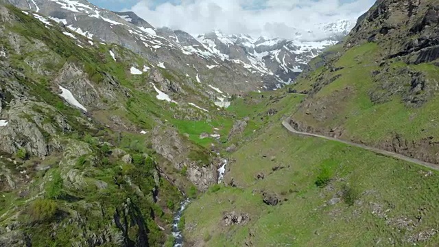 空中:飞越高山峡谷，风景如画的瀑布，雪山山脉和戏剧性的道路视频素材