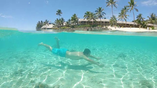 慢动作:一个活跃的男子在夏天在阳光明媚的热带岛屿附近潜水。视频素材