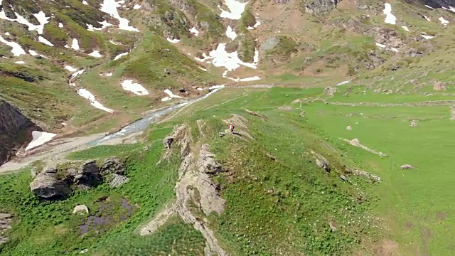 空中飞行:在山顶上绕着两个徒步旅行者飞行视频素材