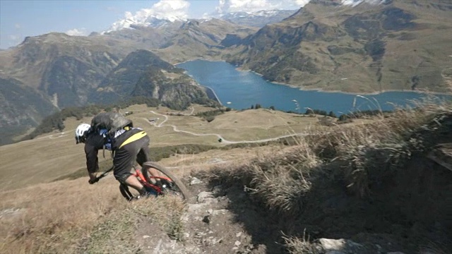 骑山地车的人在山区的岩石小道上骑车下山。——慢动作视频素材