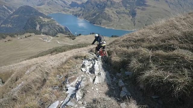 骑山地车的人在山区的岩石小道上骑车下山。——慢动作视频素材