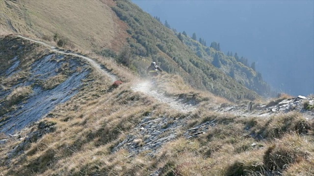 骑山地车的人在山区的岩石小道上骑车下山。——慢动作视频素材