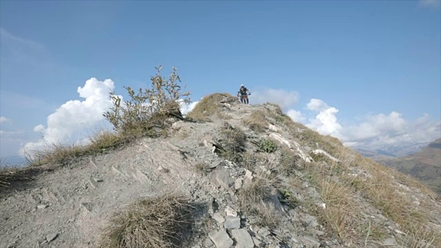 骑山地车的人在山区的岩石小道上骑车下山。——慢动作视频素材