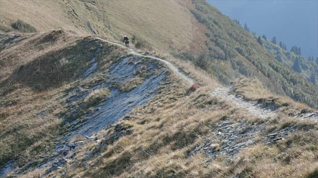 骑山地车的人在山区的岩石小道上骑车下山。——慢动作视频素材