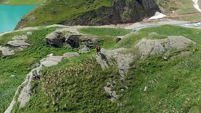 空中飞行:在山顶上绕着两个徒步旅行者飞行视频素材