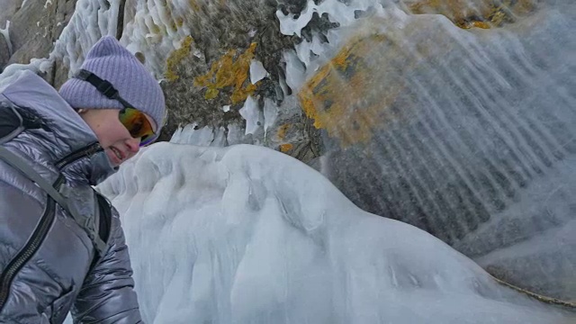 女人在贝加尔湖冰面上的旅行。冬岛之旅。女孩在冰岩石下行走。游客看着美丽的冰洞。极限跋涉和步行。背包客在大自然中休憩。视频素材