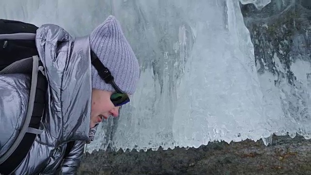 女人在贝加尔湖冰面上的旅行。冬岛之旅。女孩在冰岩石下行走。游客看着美丽的冰洞。极限跋涉和步行。背包客在大自然中休憩。视频素材