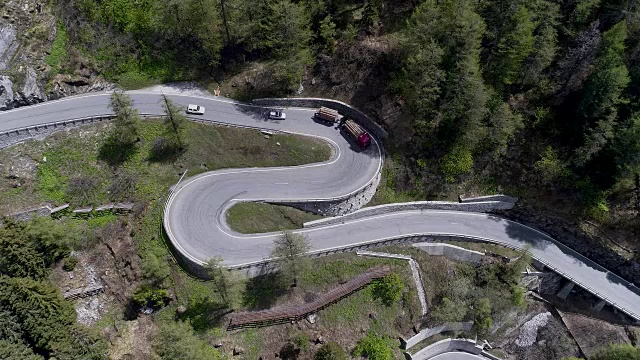 鸟瞰图山上蜿蜒的道路与卡车和汽车行驶在曲折起伏的欧洲瑞士4K视频素材