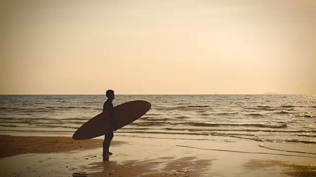 4 k。热带海滩上，日落时分，冲浪者的剪影与长长的冲浪板站在海滩上，复古的颜色风格视频素材