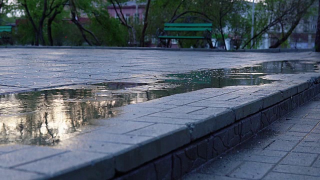 可爱的小女孩拿着五颜六色的雨伞在夕阳下穿过公园的水坑视频素材