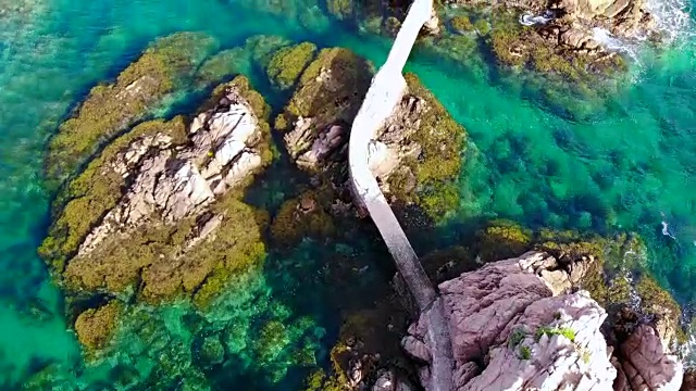 无人机在科斯塔布拉瓦海岸线的岩石之间飞过一条漂亮的路径的鸟瞰图。视频素材