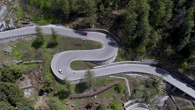 鸟瞰图山上蜿蜒的道路与卡车和汽车行驶在曲折起伏的欧洲瑞士4K视频素材