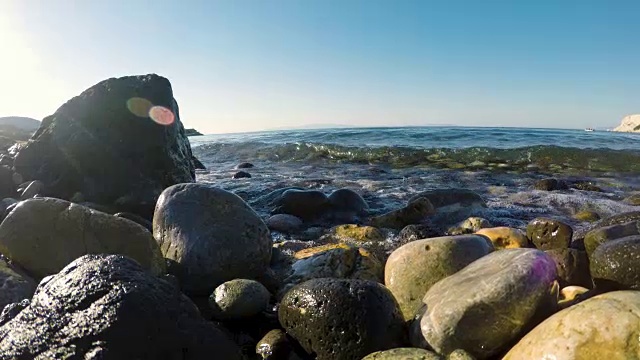 海浪和水溅到靠近水边的多石海滩上的石头上。视频素材