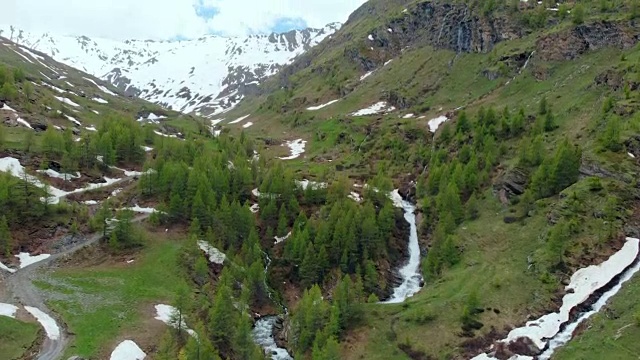 空中:飞越高山峡谷，风景如画的瀑布，雪山山脉和戏剧性的道路视频素材