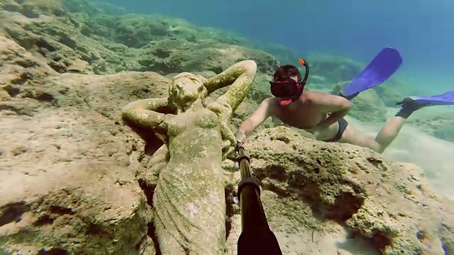 年轻人潜水去看海底的雕像视频素材