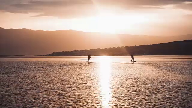 在平静的海面上站立划桨，日出视频素材