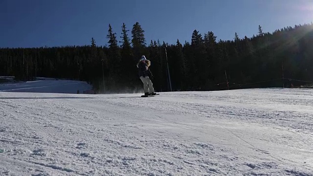 美丽的年轻女子用滑雪板滑下滑雪坡视频素材