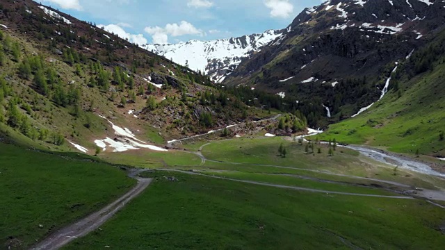 空中:飞越高山峡谷，风景如画的瀑布，雪山山脉和戏剧性的道路视频素材