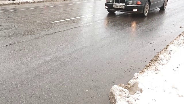 肮脏的冬季道路上有水坑和雪。行人过街与汽车。视频素材