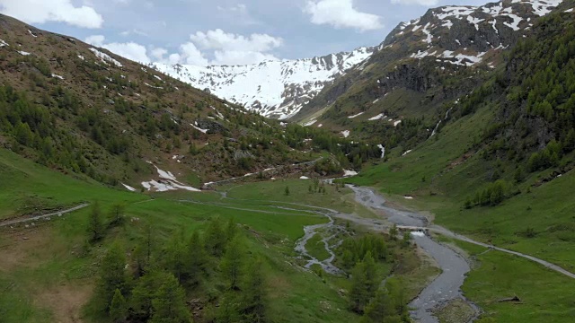 空中:飞越高山峡谷，风景如画的瀑布，雪山山脉和戏剧性的道路视频素材