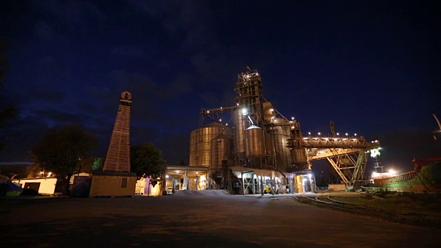 夜间全景图的粮食作物装载在散货船船通过后备箱打开货仓仓在海港从卡车。谷物主要转运。运输农产品视频素材