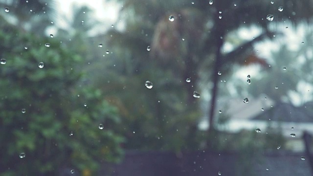 慢镜头:小雨滴从乌云密布的天空和热带海滩上落下。视频素材