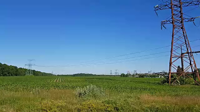 数英里的架空电力线通过高压电线形成了一个输电网。夏日的田野，阳光灿烂。视频素材