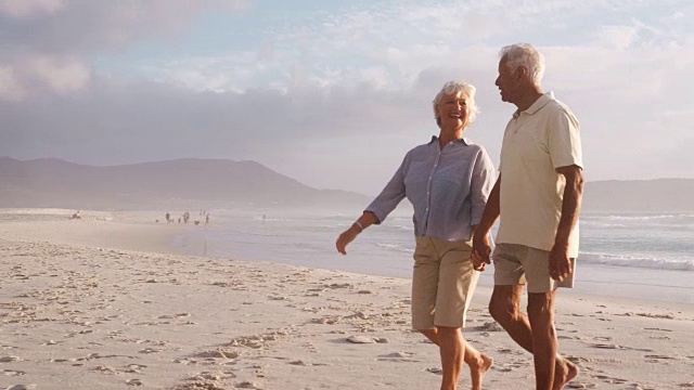 一对浪漫的老年夫妇在夏天沿着海滩散步视频素材