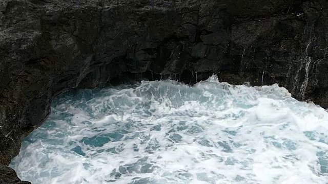 巨浪冲击着熔岩峭壁。缓慢的运动。视频素材