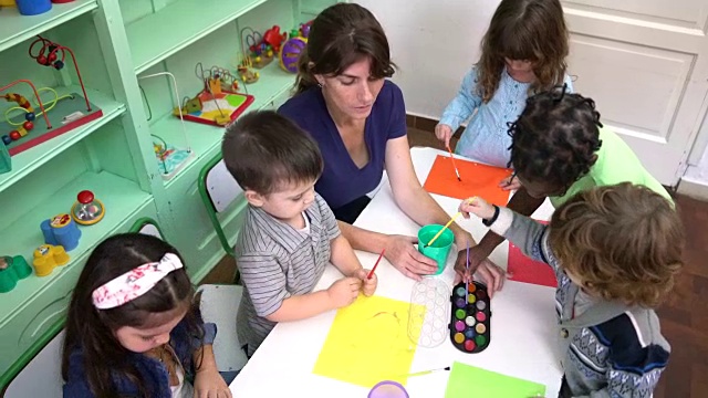 幼儿园的孩子在教室里和老师一起画画视频素材